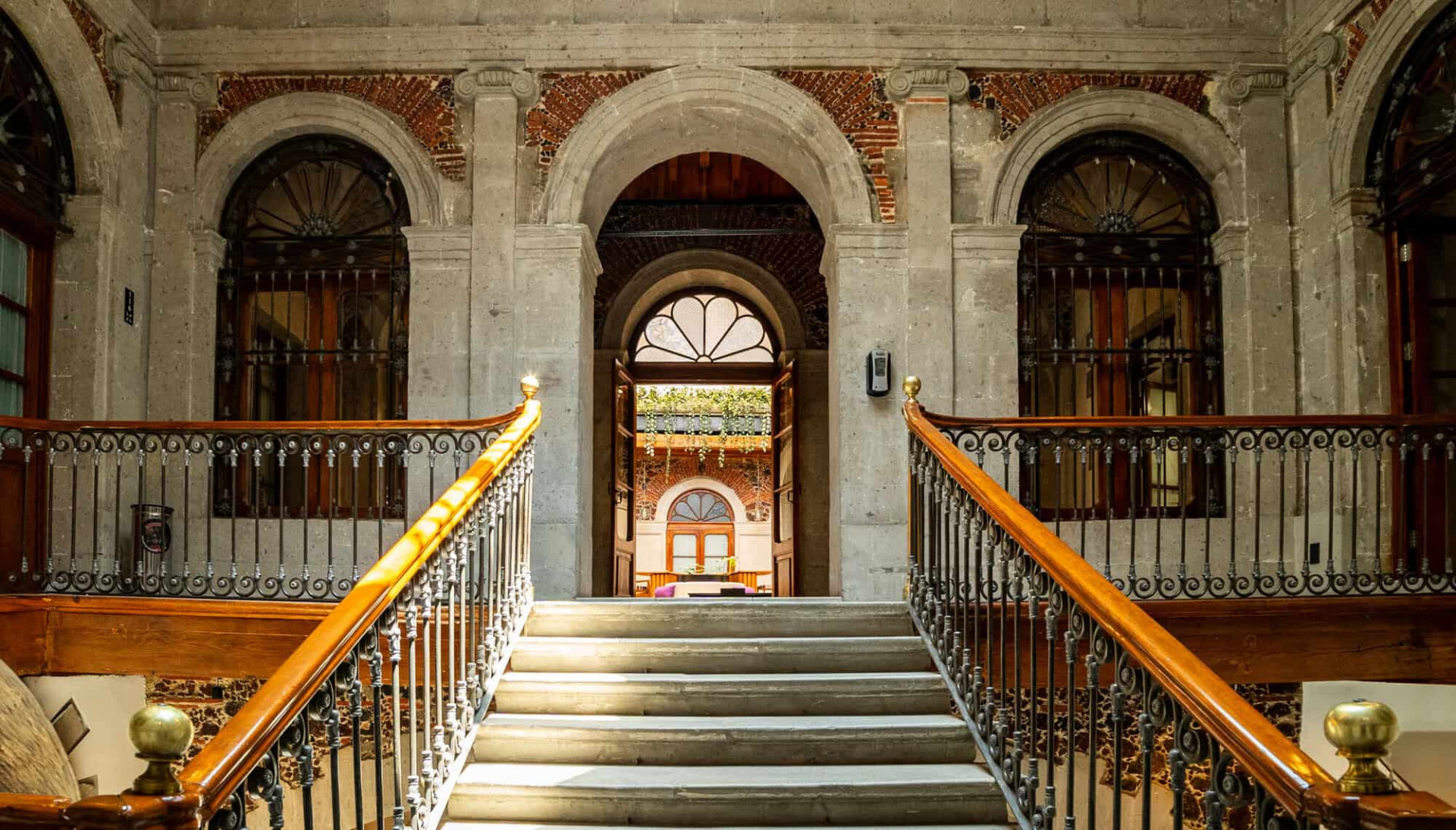 Escalera principal iluminada por el sol en Casa de la Luz, hotel boutique en Ciudad de México