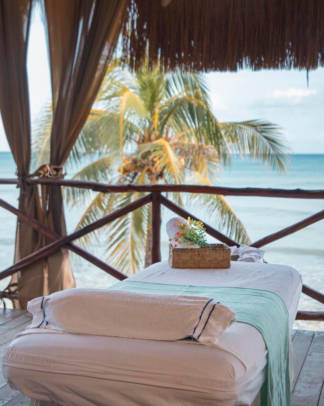 Cama de masajes con techo de palapa y vistas a la playa 