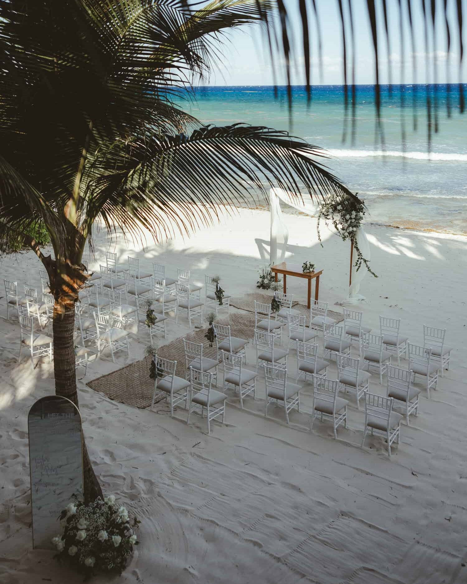 Altar blanco con sillas blancas en la arena frente al mar para una boda en MVNGATA 
