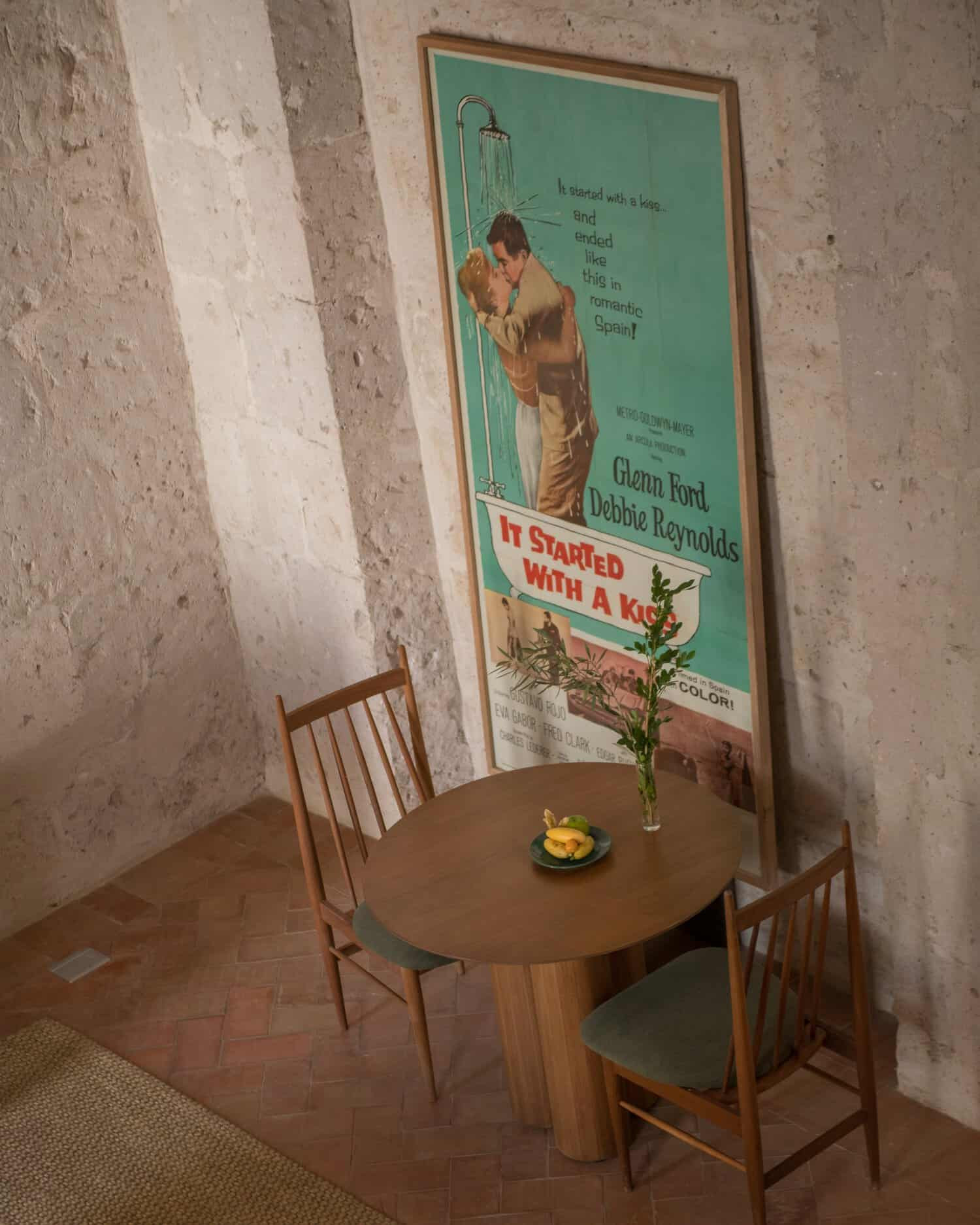 Mesa y silla junto a un poster vintage de película. 
