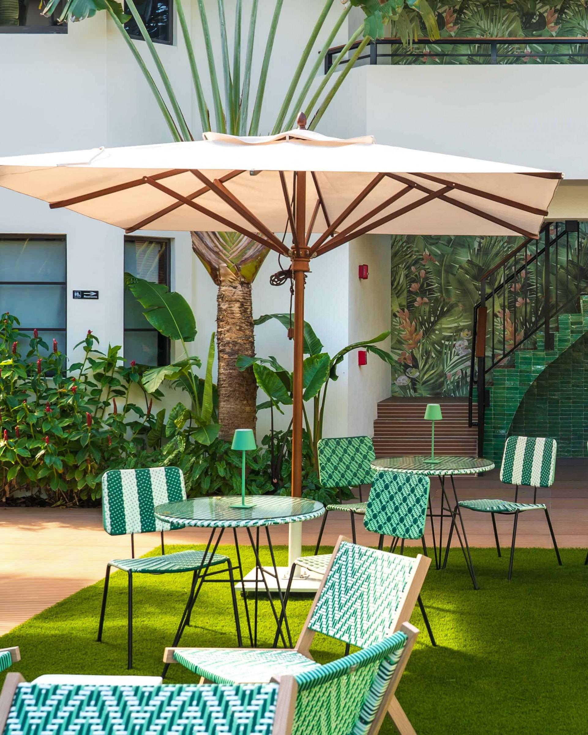 Mesas y sombrillas de diseño contemporáneo en el patio interior de Maison Felix  