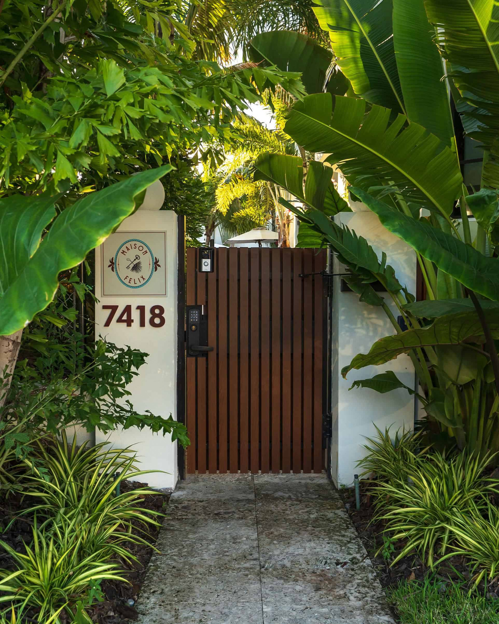 La puerta de entrada a Maison Felix discreta y rodeada de planta tropicales 