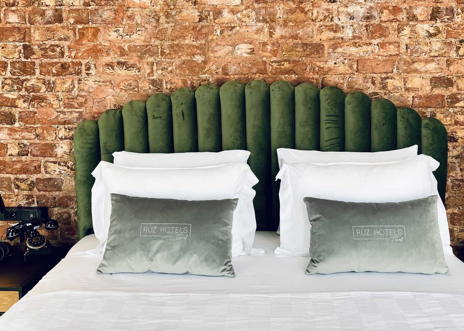 Exposed brick and velvet green bed in hotel boutique RUZ Hotels in Istanbul