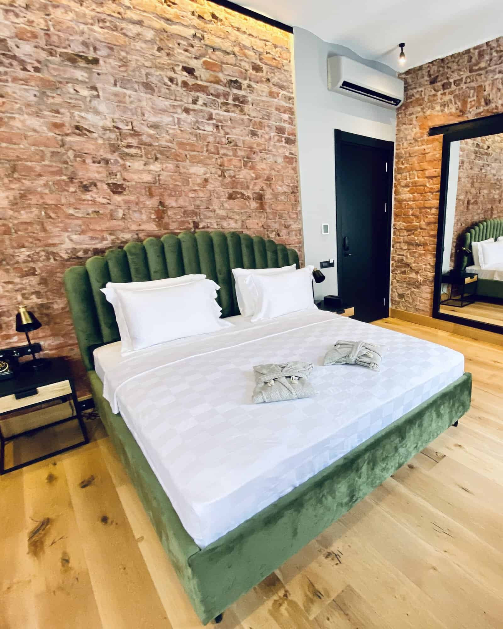 Elegant room with exposed brick and velvet green bed