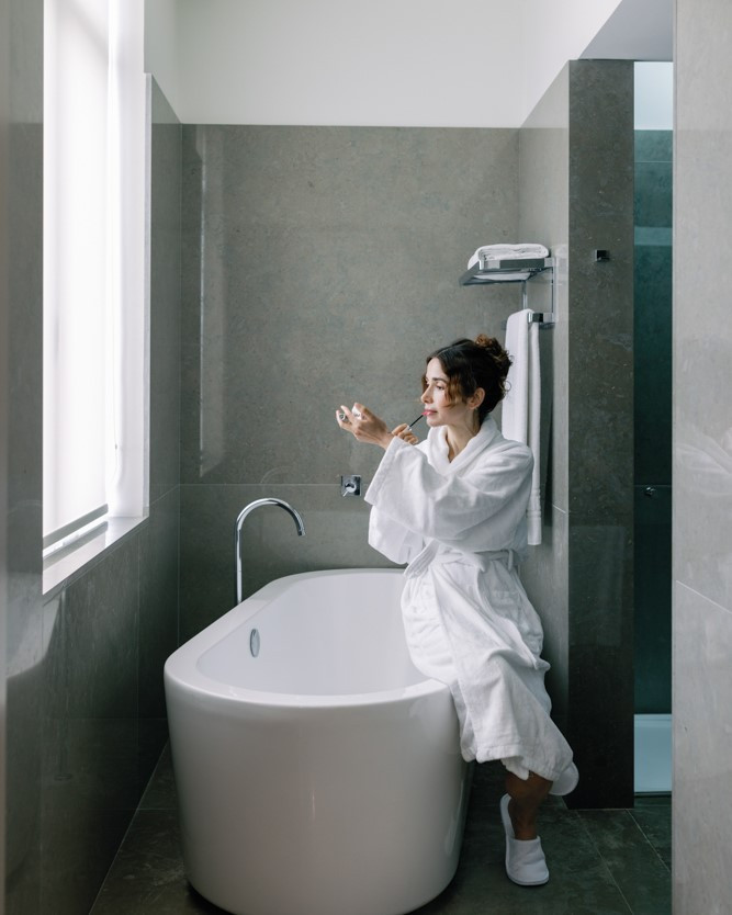 Bathroom with a bathtub and a window letting in natural light in a suite at The Editory Artist Baixa.
