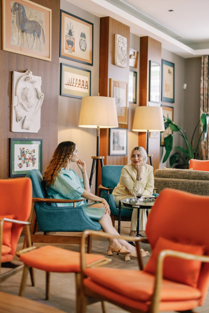 Colourful hotel lounge with artwork, sofas, and armchairs.